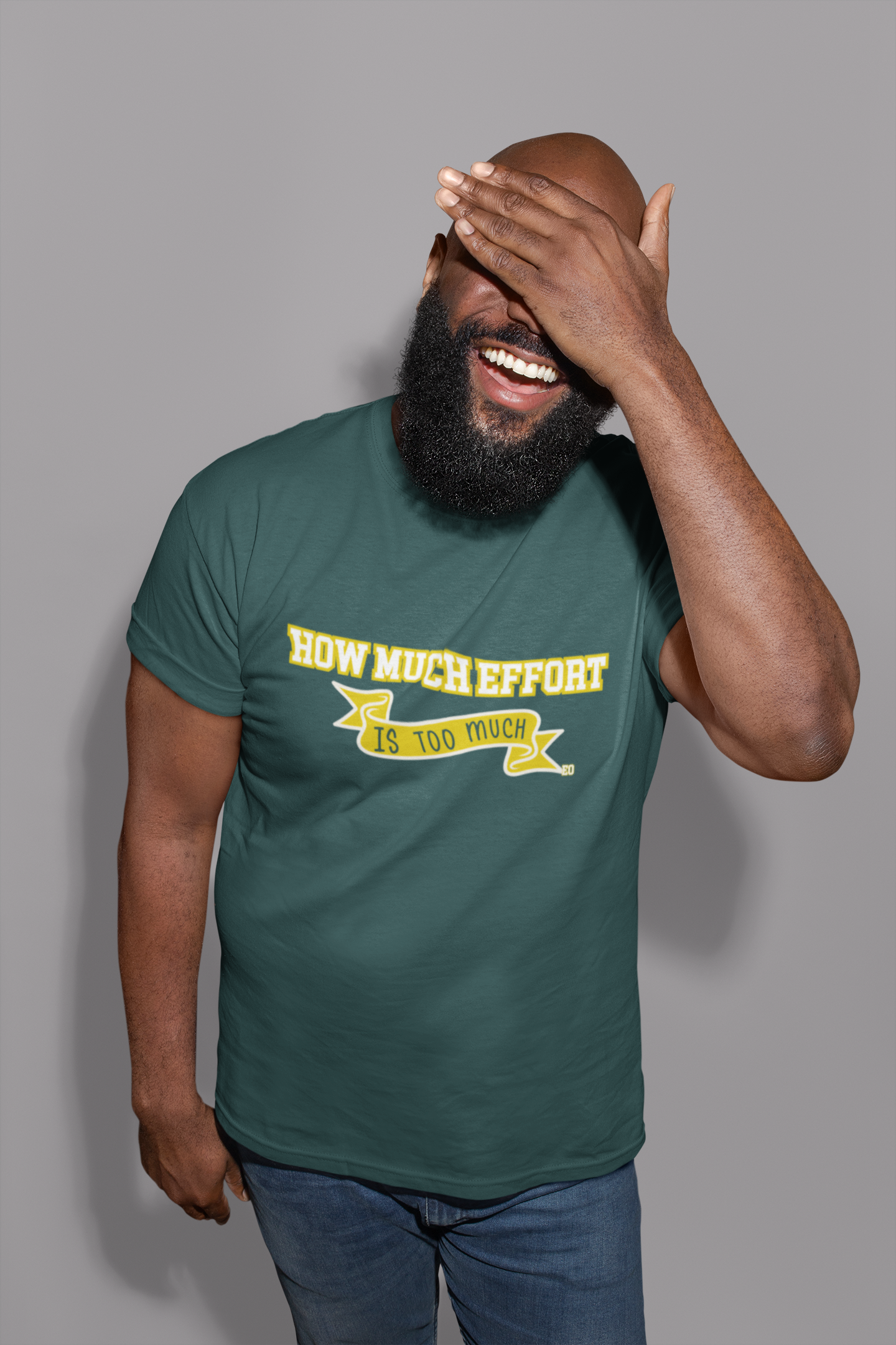Man wearing a green t-shirt with yellow text, laughing against a gray background