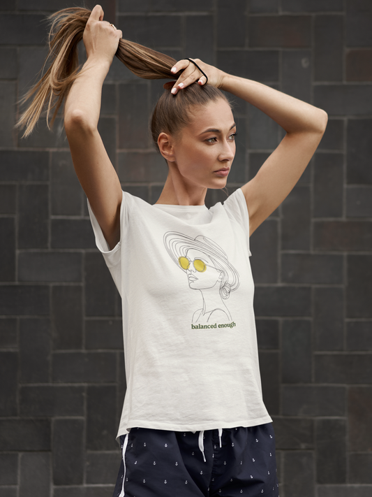 Woman wearing a white t-shirt with a graphic design against a dark tiled wall.
