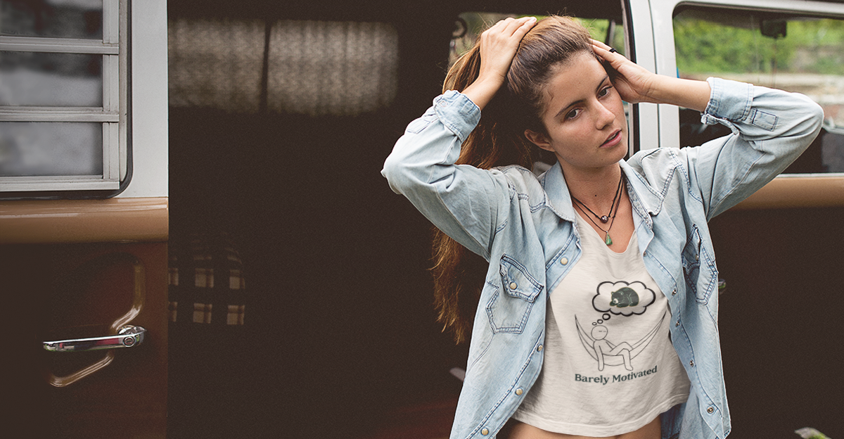 Woman wearing a denim jacket and a white t-shirt with a graphic design, standing in front of a vehicle.