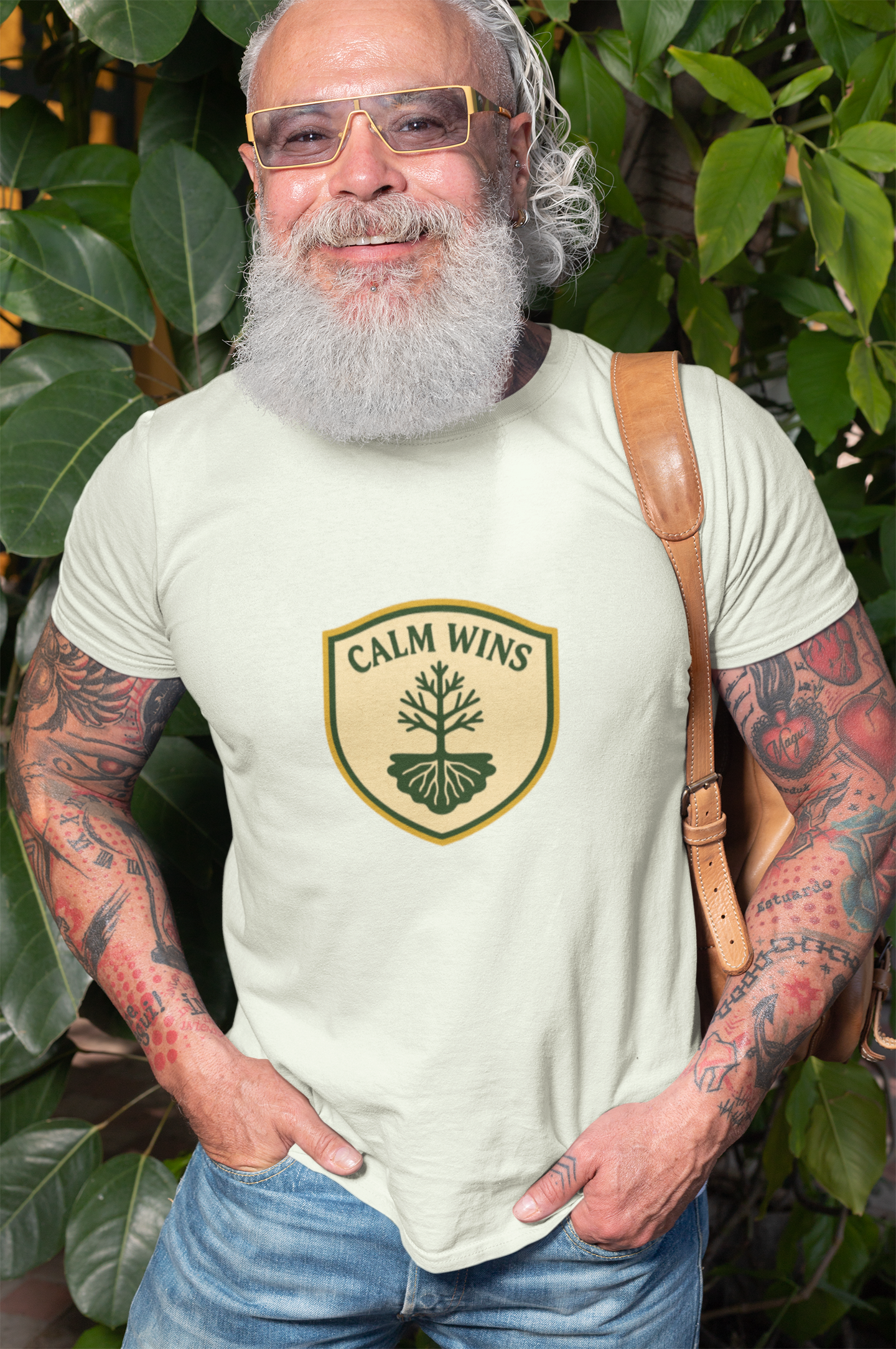 Man wearing a t-shirt with 'Calm Wins' logo amidst green foliage