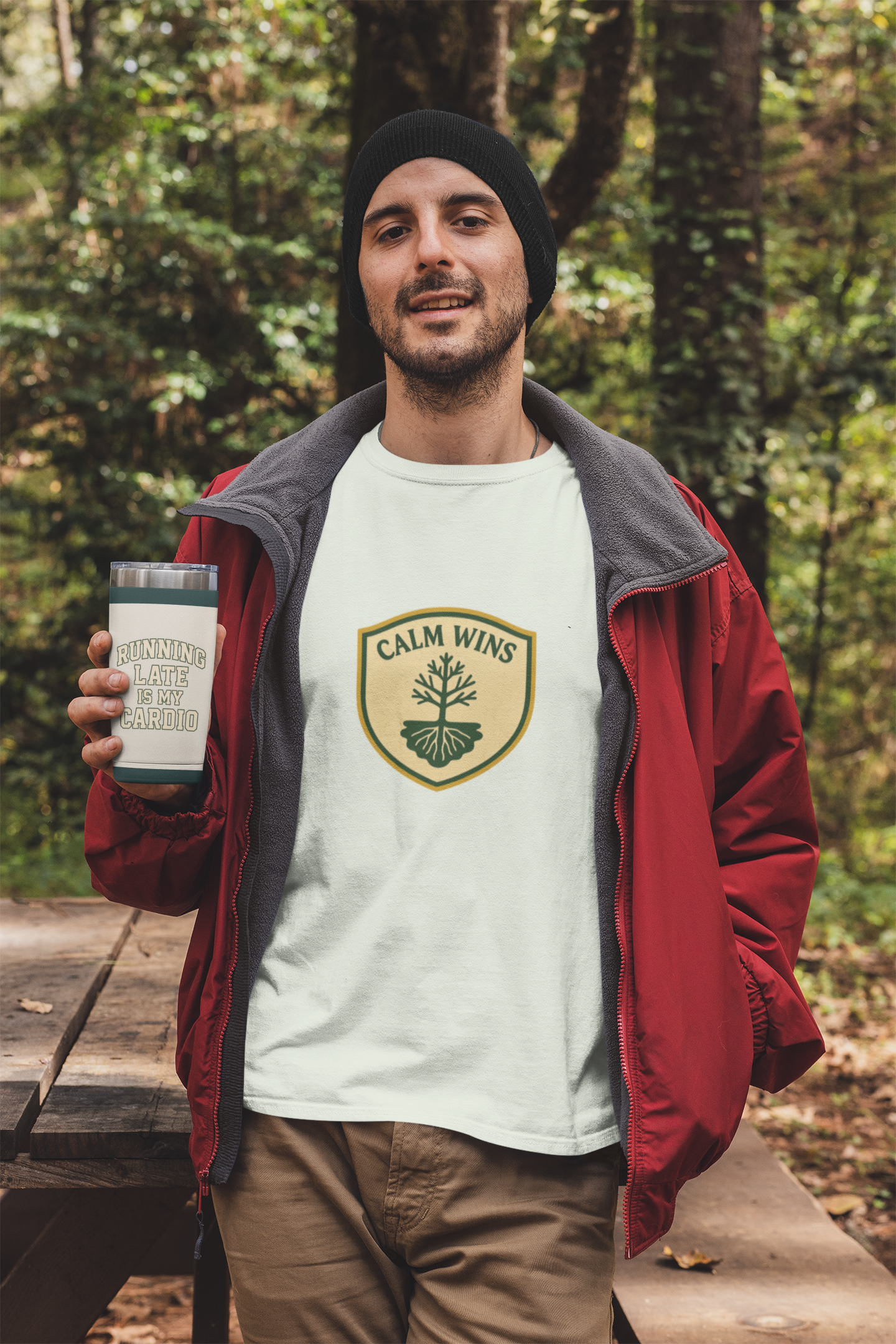 Man holding a tumbler with a 'Calm Wins' logo in a forest setting