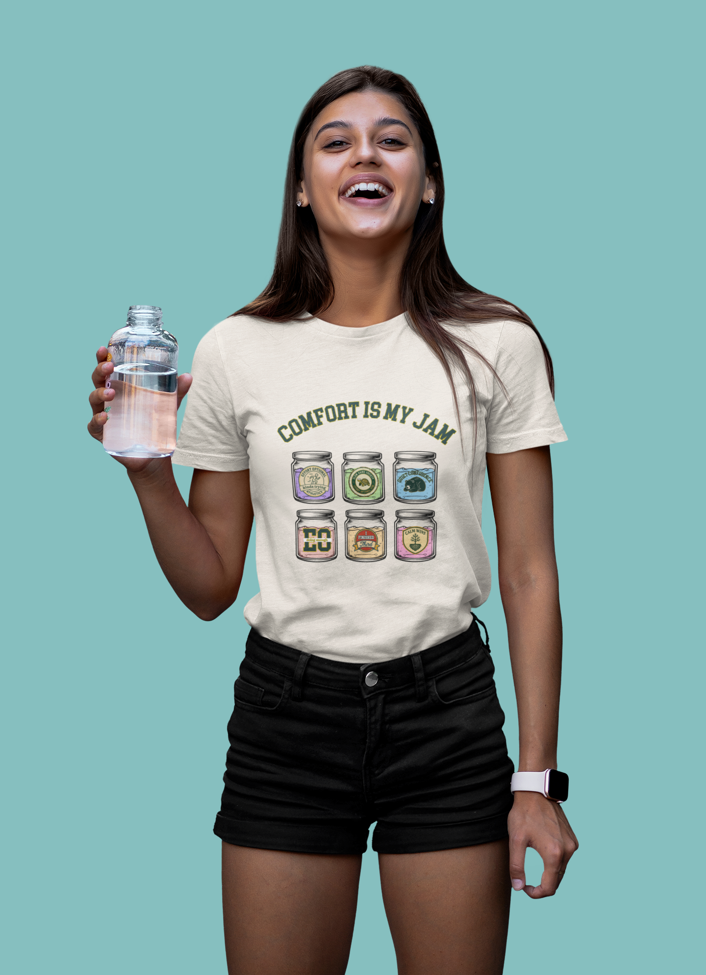 Woman wearing a t-shirt with 'Comfort is My Jam' graphic holding a water bottle against a teal background