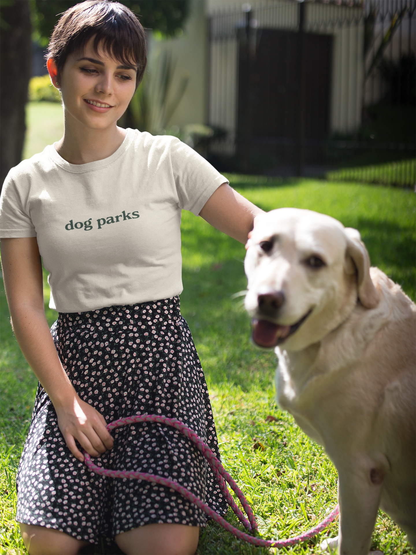 Woman in 'dog parks' t-shirt with a dog on a leash in a park
