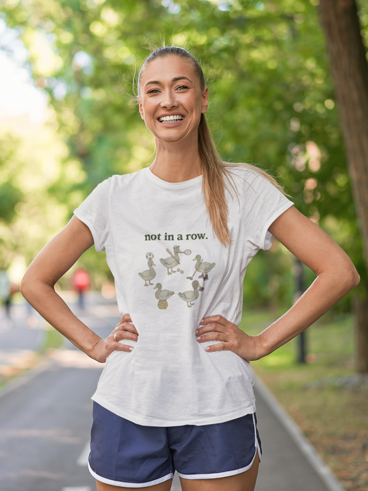 Woman wearing a white t-shirt with a graphic design and text, standing outdoors on a path.