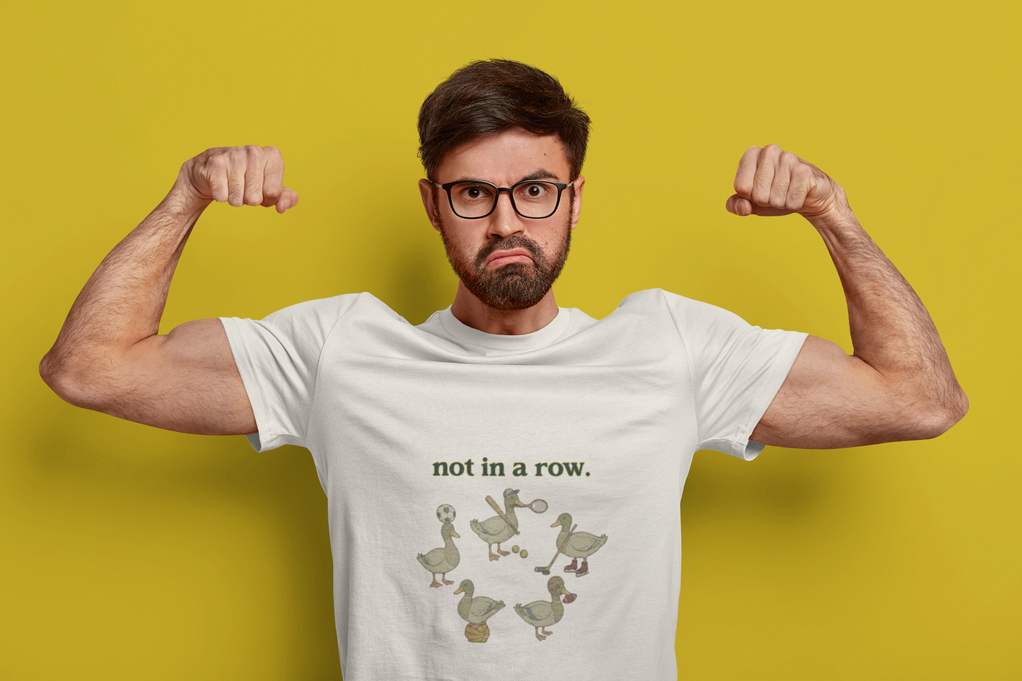 Man flexing muscles wearing a white t-shirt with a graphic design on a yellow background