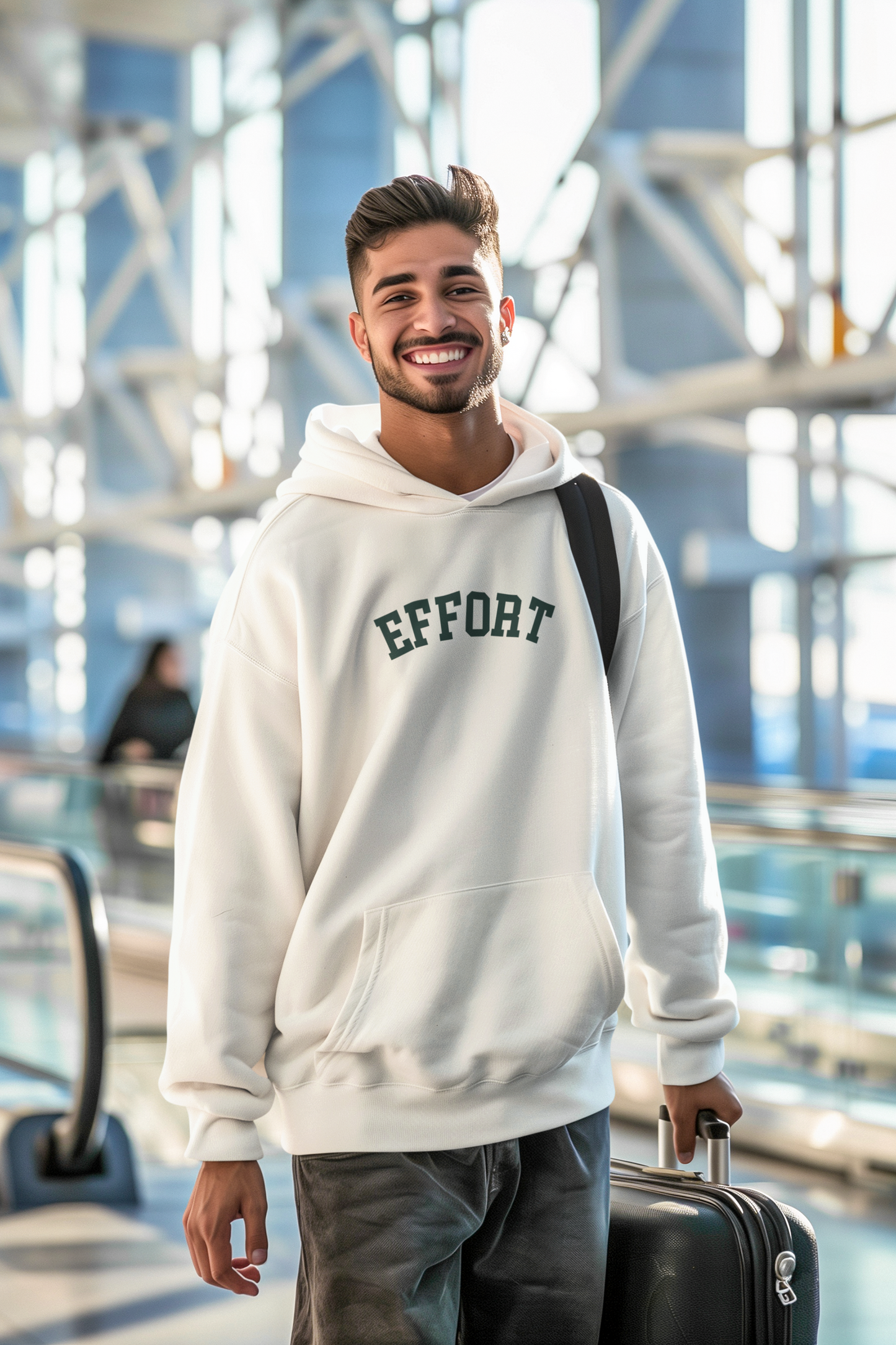 Man wearing a hoodie with 'EFFORT' text in an indoor setting, possibly an airport.