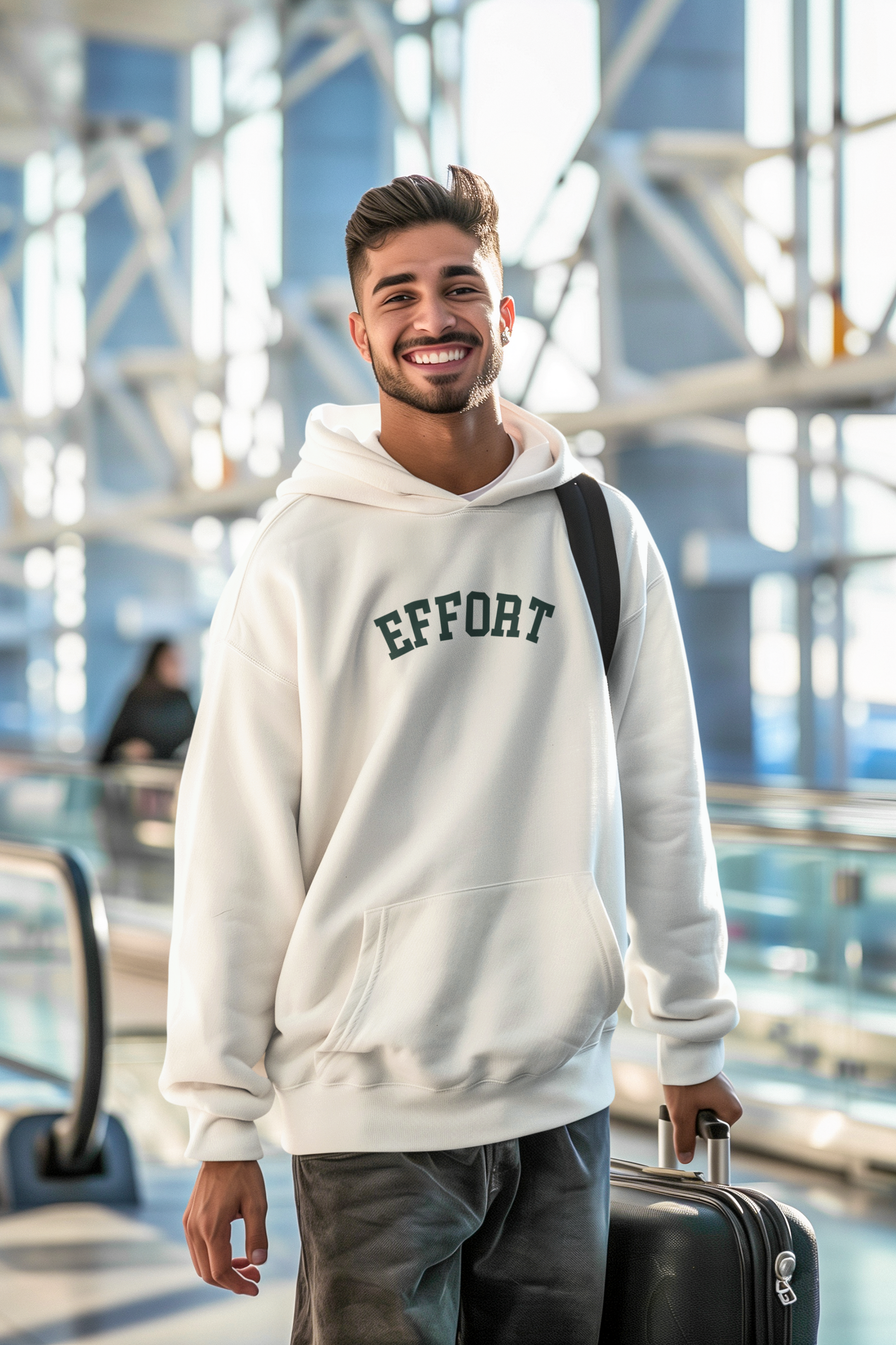 Man wearing a hoodie with 'EFFORT' text in an indoor setting, possibly an airport.