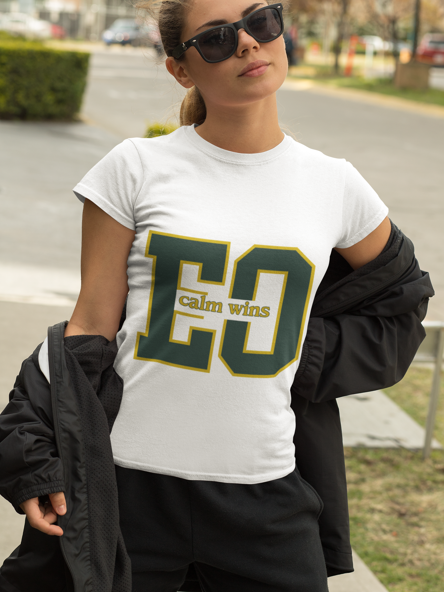 Person wearing a white t-shirt with 'CO calm wins' text outdoors.