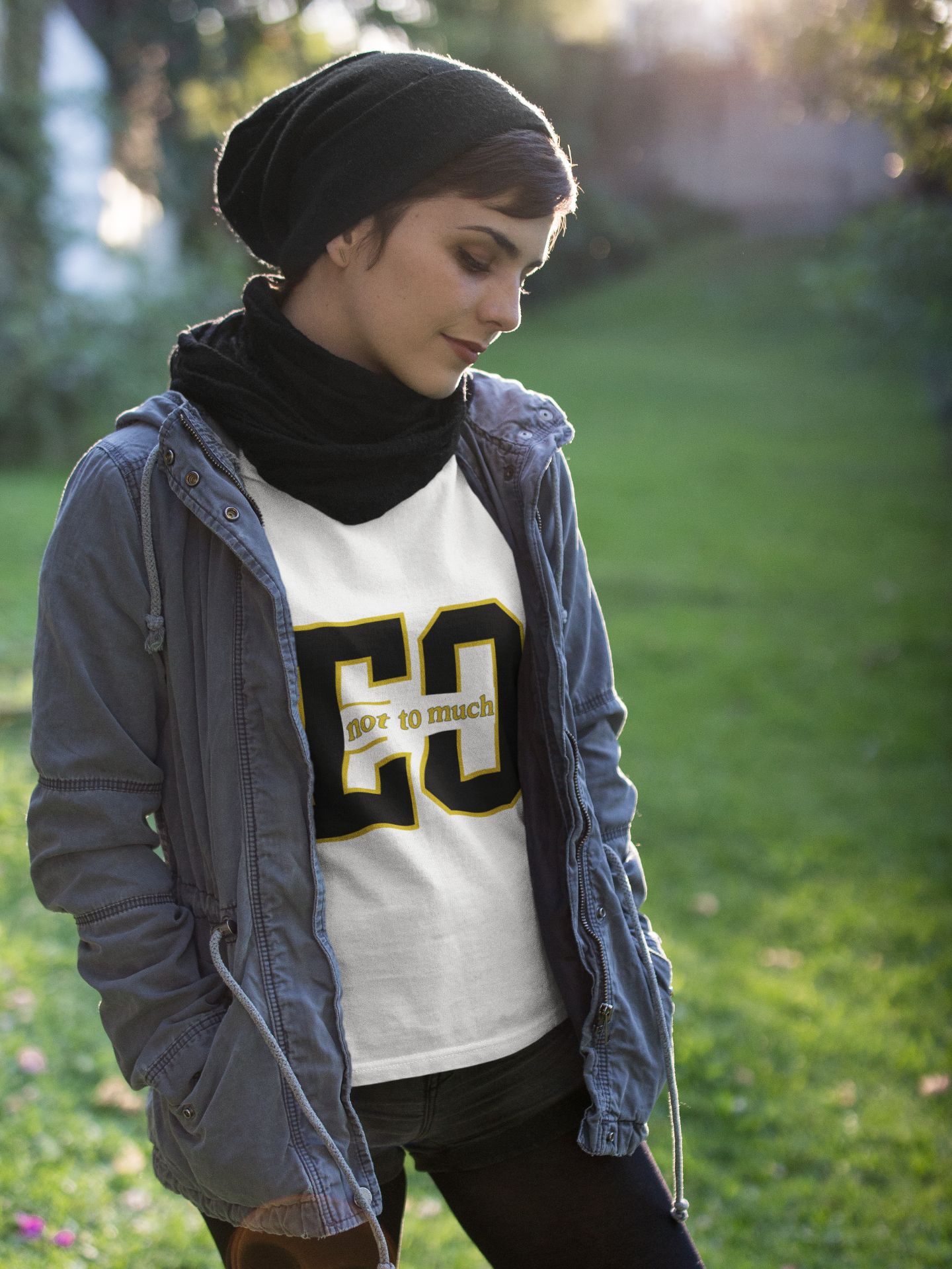 Person wearing a gray jacket and white sweatshirt with text, standing outdoors on grass.