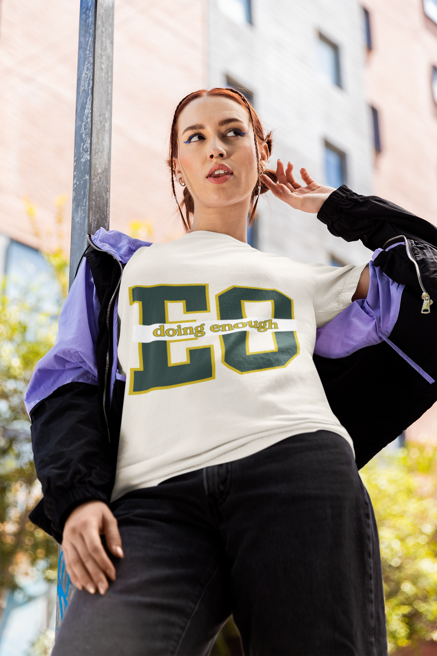 Person wearing a white sweatshirt with 'EC doing enough' text, standing outdoors.