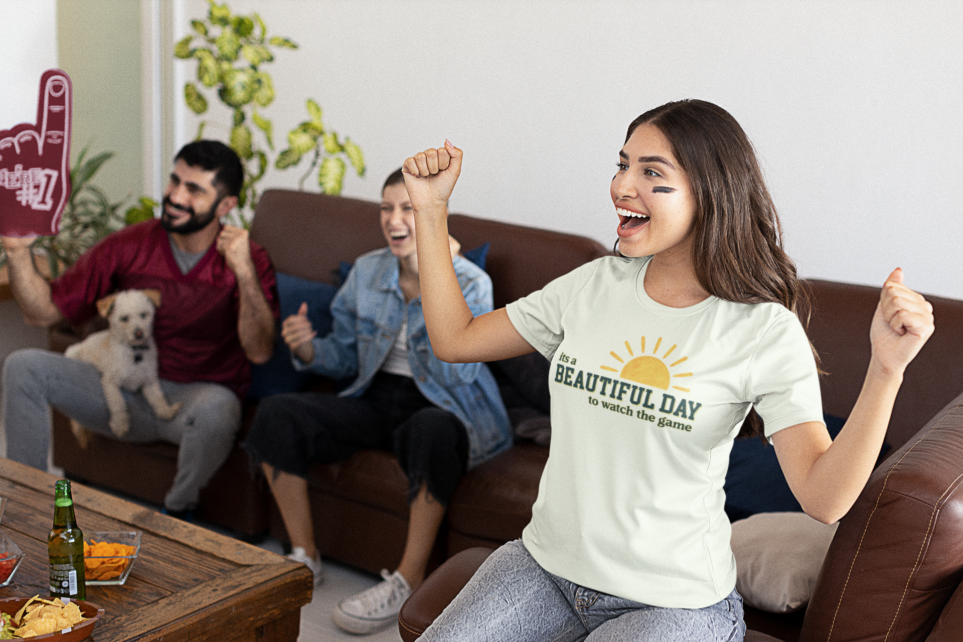Woman in a 'It's a Beautiful Day' t-shirt cheering with friends on a couch.