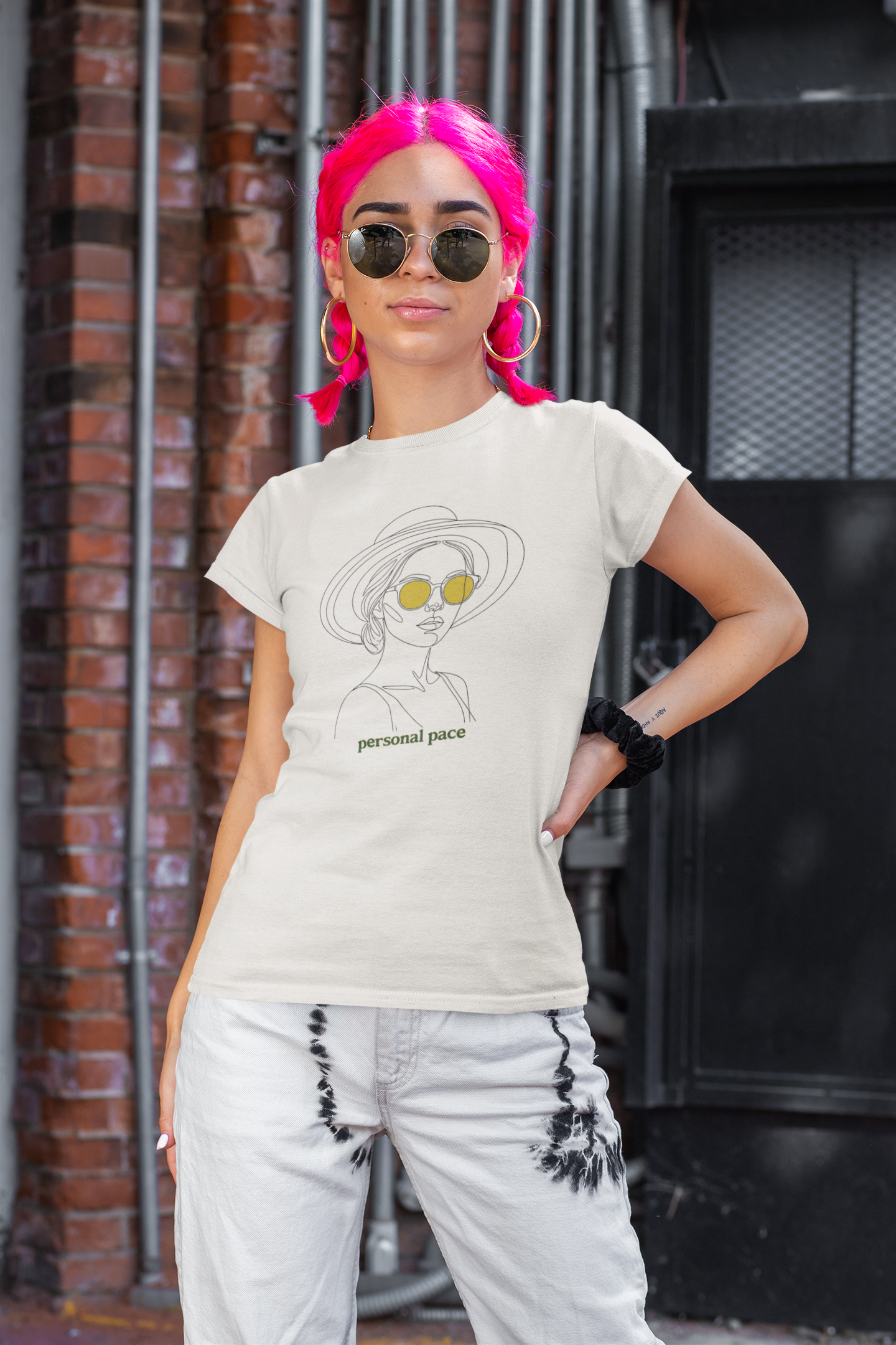 Person wearing a t-shirt with a graphic design and text, standing against an urban background.