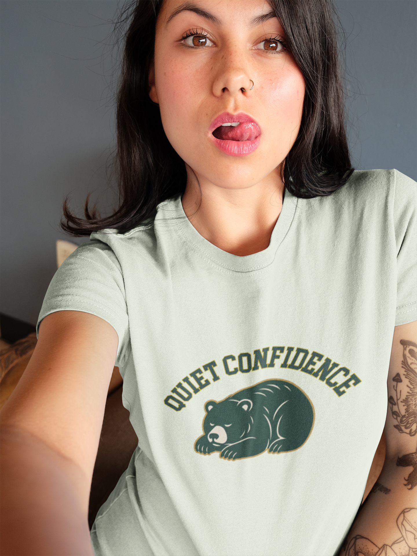 Person wearing a light green t-shirt with 'Quiet Confidence' and a bear graphic.