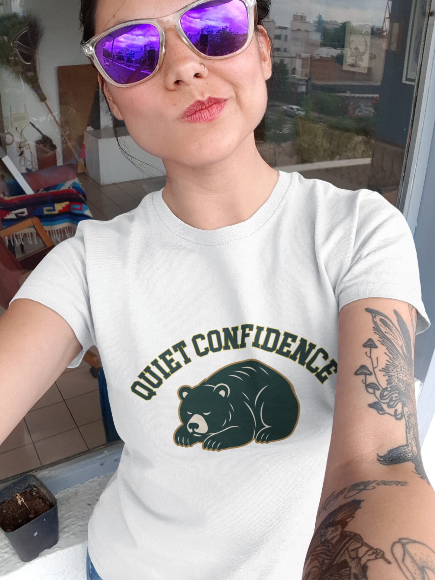 Person wearing a white t-shirt with a bear graphic and 'Quiet Confidence' text, sitting indoors.