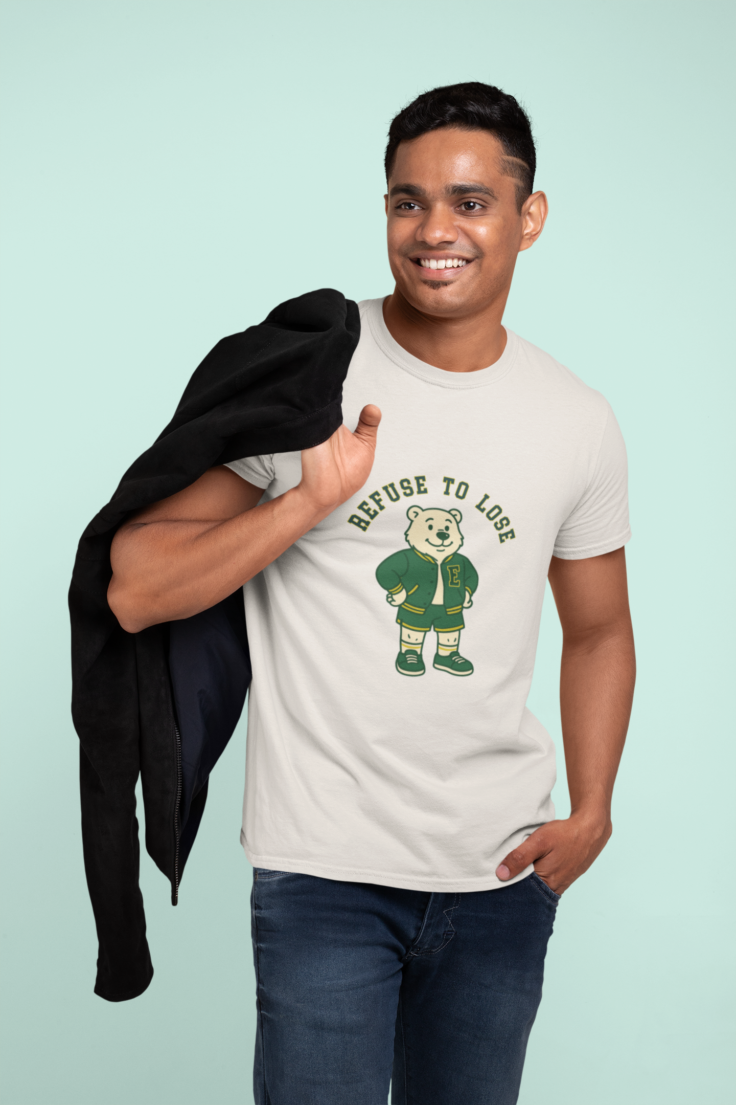 Man wearing a t-shirt with a bear graphic and text, holding a black jacket against a light blue background
