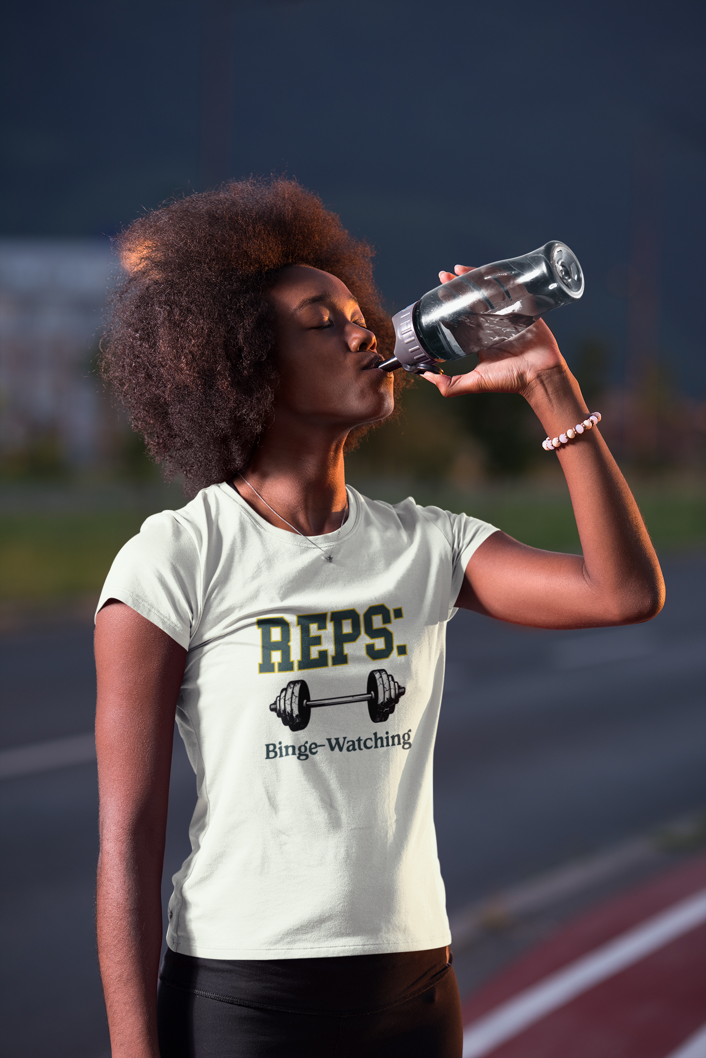 Person drinking water on a track wearing a t-shirt with 'REPS: Binge-Watching' text.
