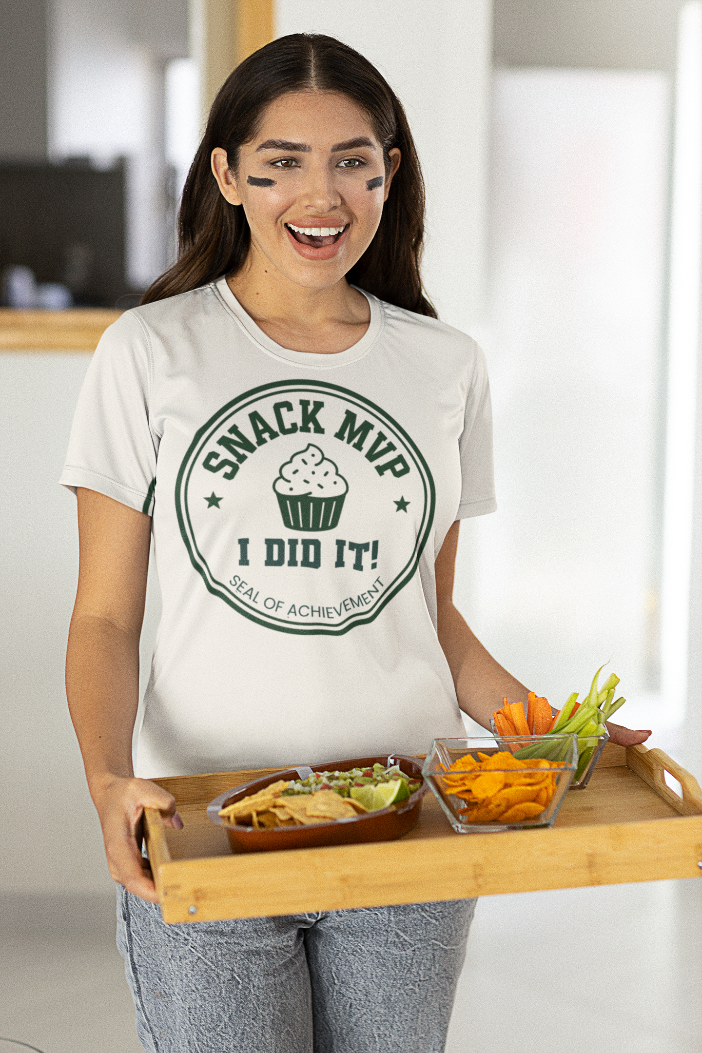 Woman wearing a 'Snack MVP' t-shirt holding a tray of snacks.