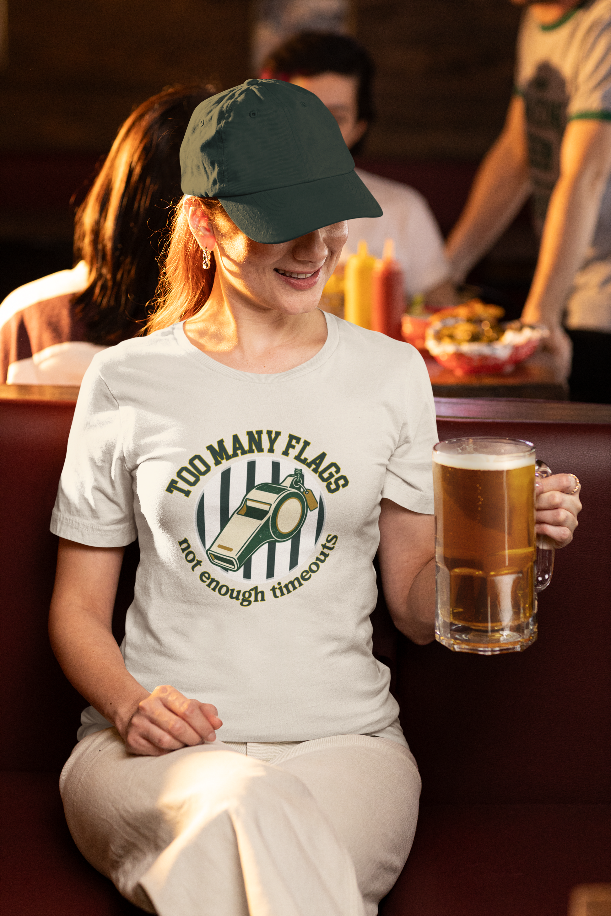Person wearing a white t-shirt with a graphic design, holding a mug of beer in a casual setting.