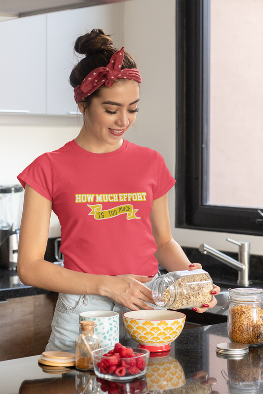 Woman in a kitchen wearing a red t-shirt with text, preparing food.