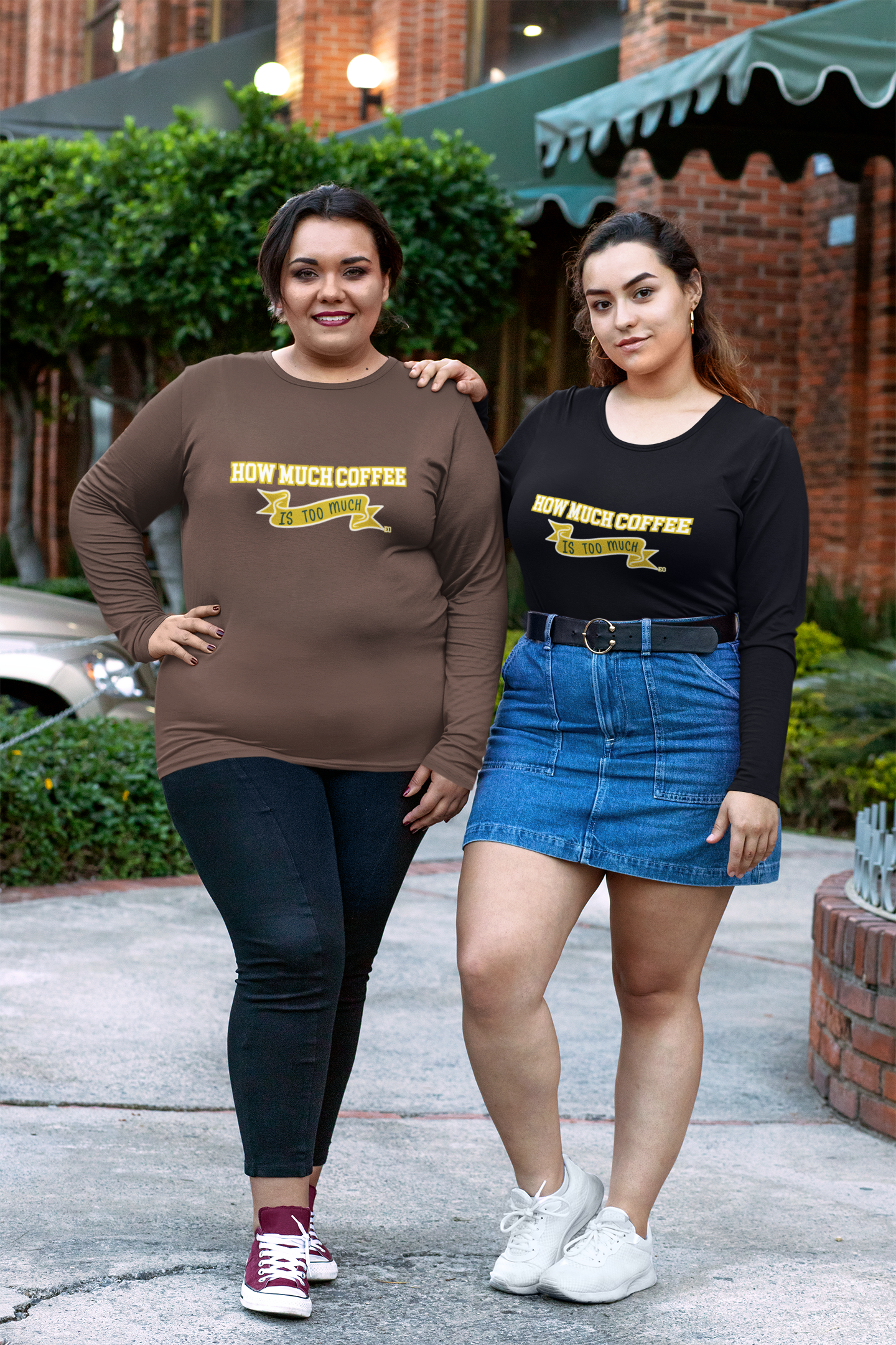 Two women wearing shirts with text standing outdoors.