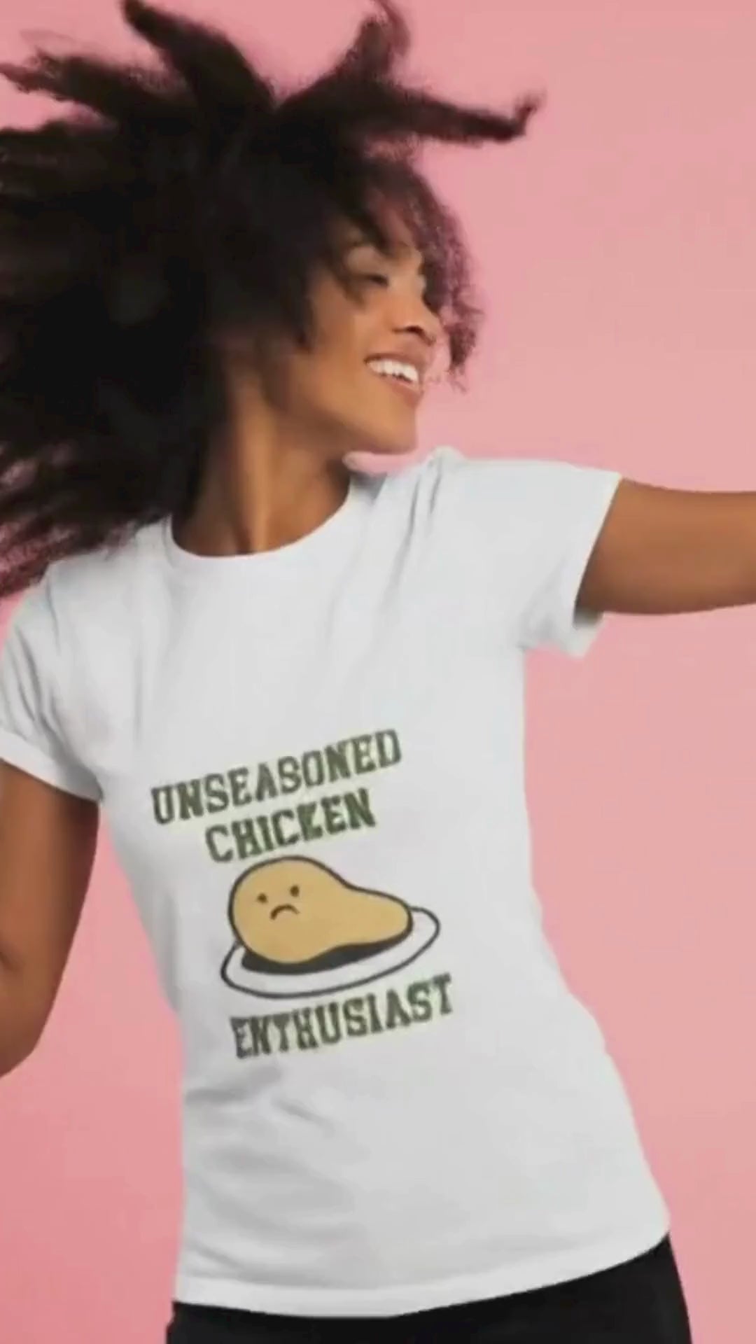 Woman wearing a t-shirt with 'Unseasoned Chicken Enthusiast' graphic on a pink background.video