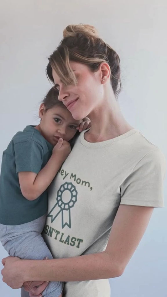 Woman holding a child wearing a t-shirt with text against a plain background.video